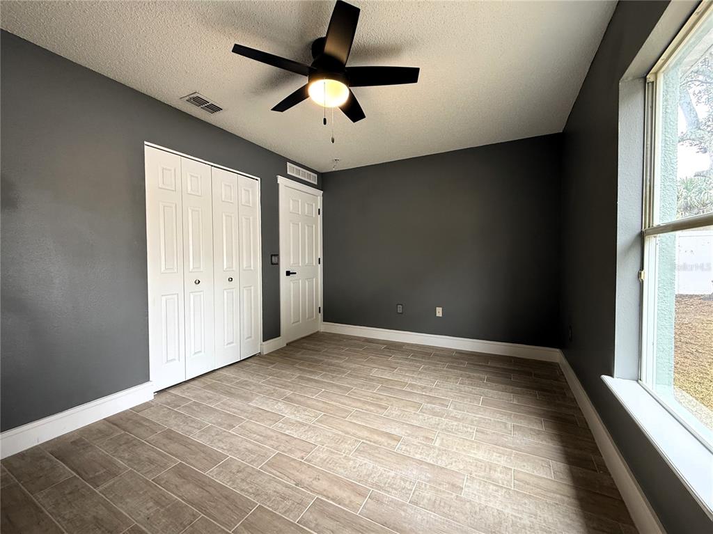 6172 Raleigh Street Spring Hill, FL 34606 - Photo 34 of 64 en empty room with windows and ceiling fan