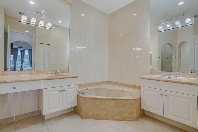 a bathroom with a granite countertop bathtub shower sink vanity and toilet