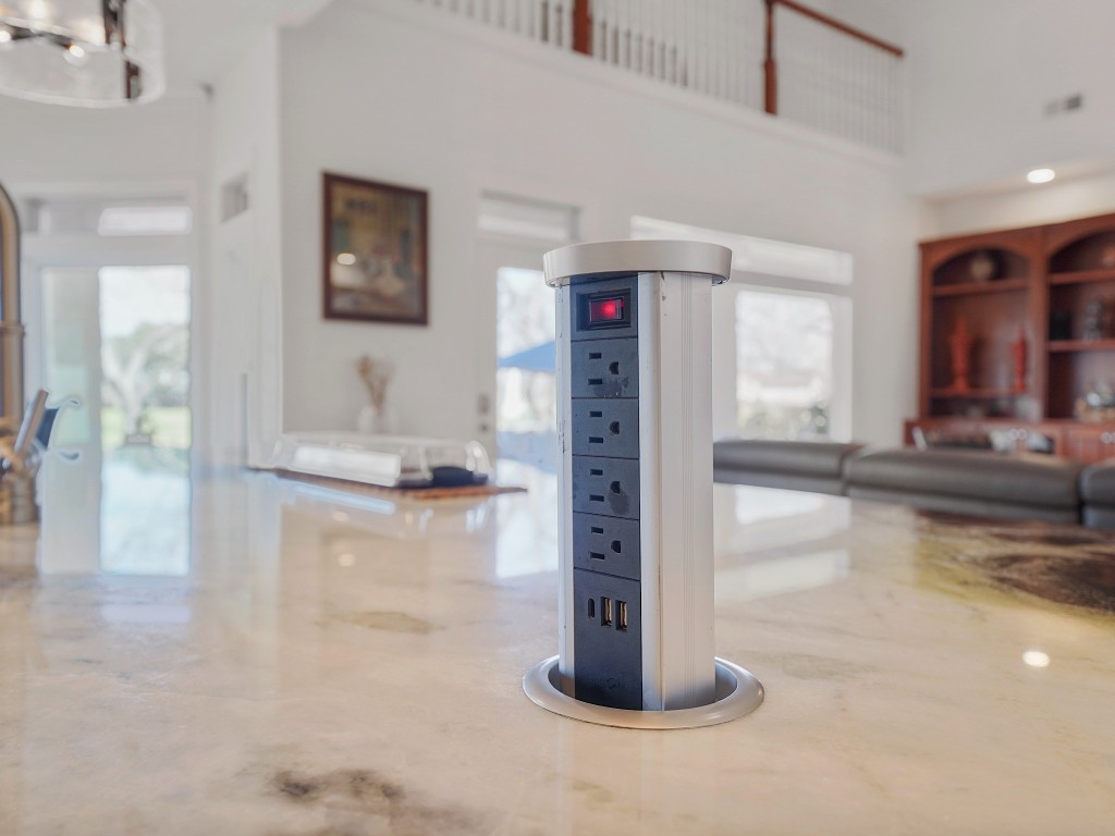 32134 Fulbrook Commons Fulshear, TX 77441 - Photo 12 of 49 The statement waterfall island is as functional as it is striking, featuring a concealed pop-up outlet tower that rises seamlessly from the countertop at the touch of a button. Integrated wireless charging adds modern convenience while preserving the clean, uninterrupted lines of this beautifully reimagined kitchen.