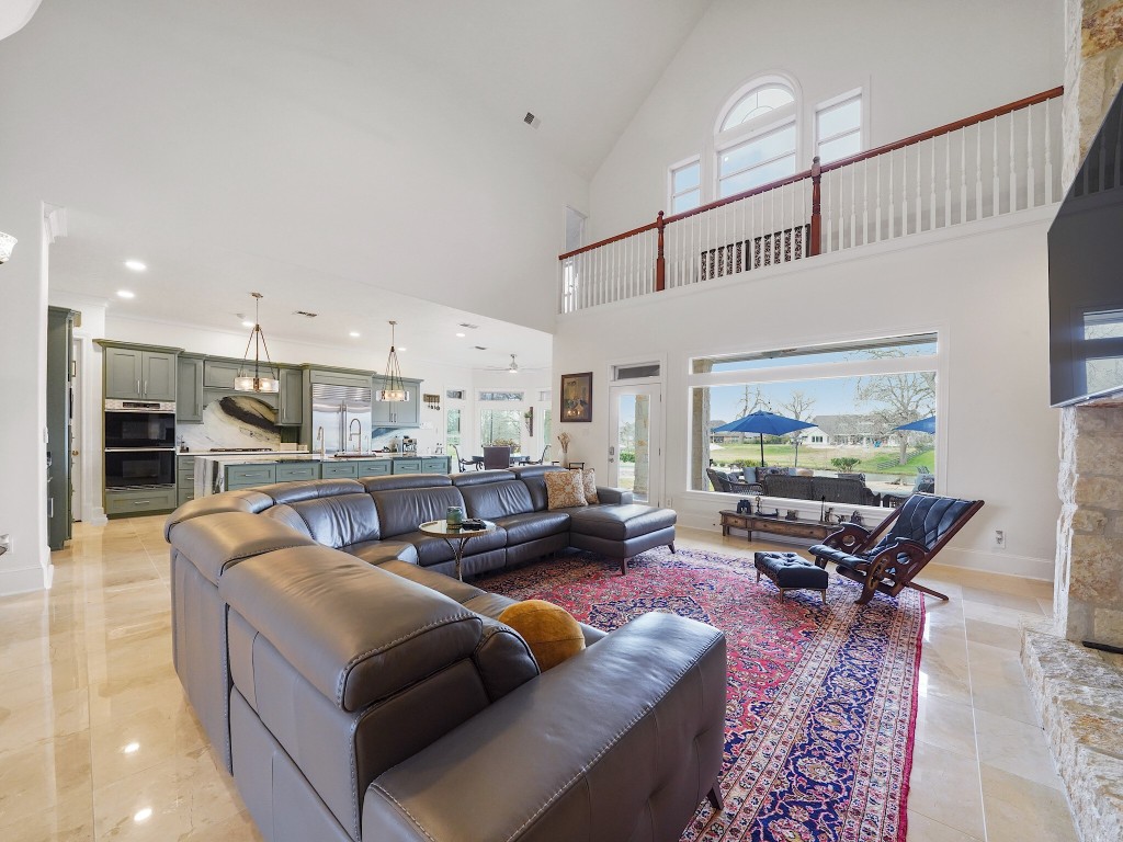 32134 Fulbrook Commons Fulshear, TX 77441 - Photo 14 of 49 The two-story living room commands attention with soaring ceilings, a dramatic stone fireplace, and expansive windows that frame the outdoor oasis and flood the space with natural light.
