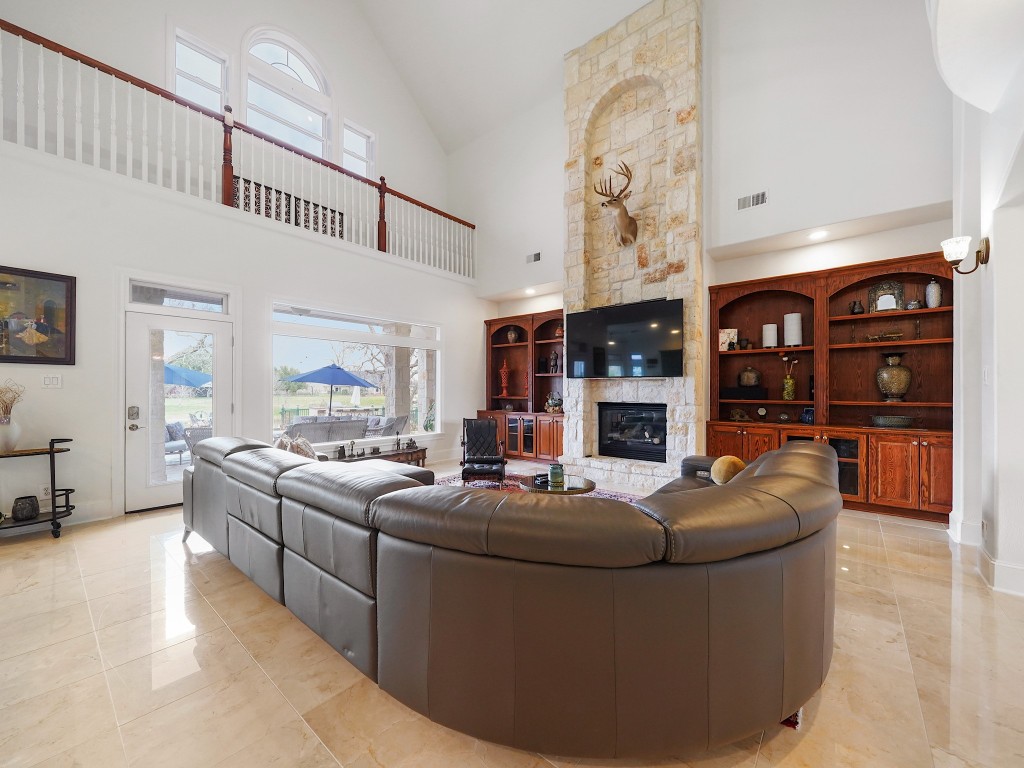 32134 Fulbrook Commons Fulshear, TX 77441 - Photo 15 of 49 Custom built-ins and a striking fireplace anchor the living space, blending warmth and architectural detail to create a refined yet inviting gathering area.