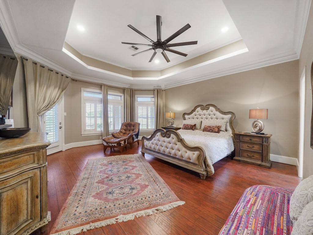 32134 Fulbrook Commons Fulshear, TX 77441 - Photo 18 of 49 The primary suite is a private sanctuary, offering generous proportions, tray ceilings, rich hardwood flooring, and serene views that create a calm and restorative atmosphere.