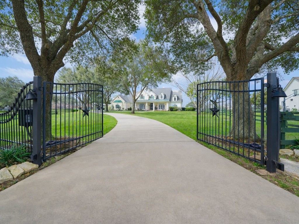 32134 Fulbrook Commons Fulshear, TX 77441 - Photo 2 of 49 A private gated entry sets the tone for arrival, offering security and exclusivity as you approach the residence beneath towering mature trees.