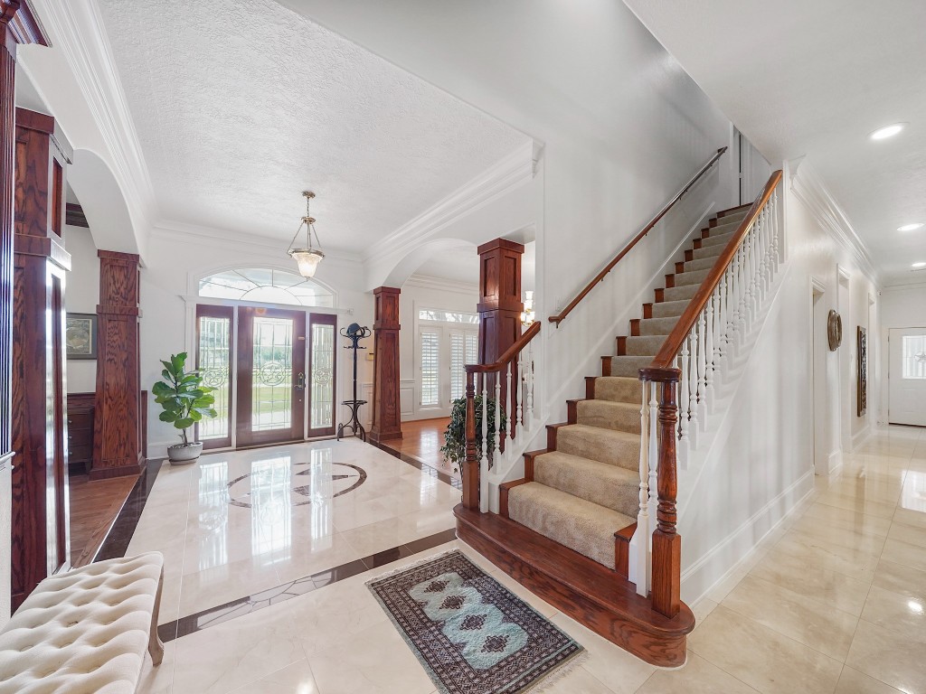32134 Fulbrook Commons Fulshear, TX 77441 - Photo 28 of 49 A graceful staircase with classic detailing rises from the grand foyer, creating a striking architectural focal point that enhances the home’s dramatic scale.