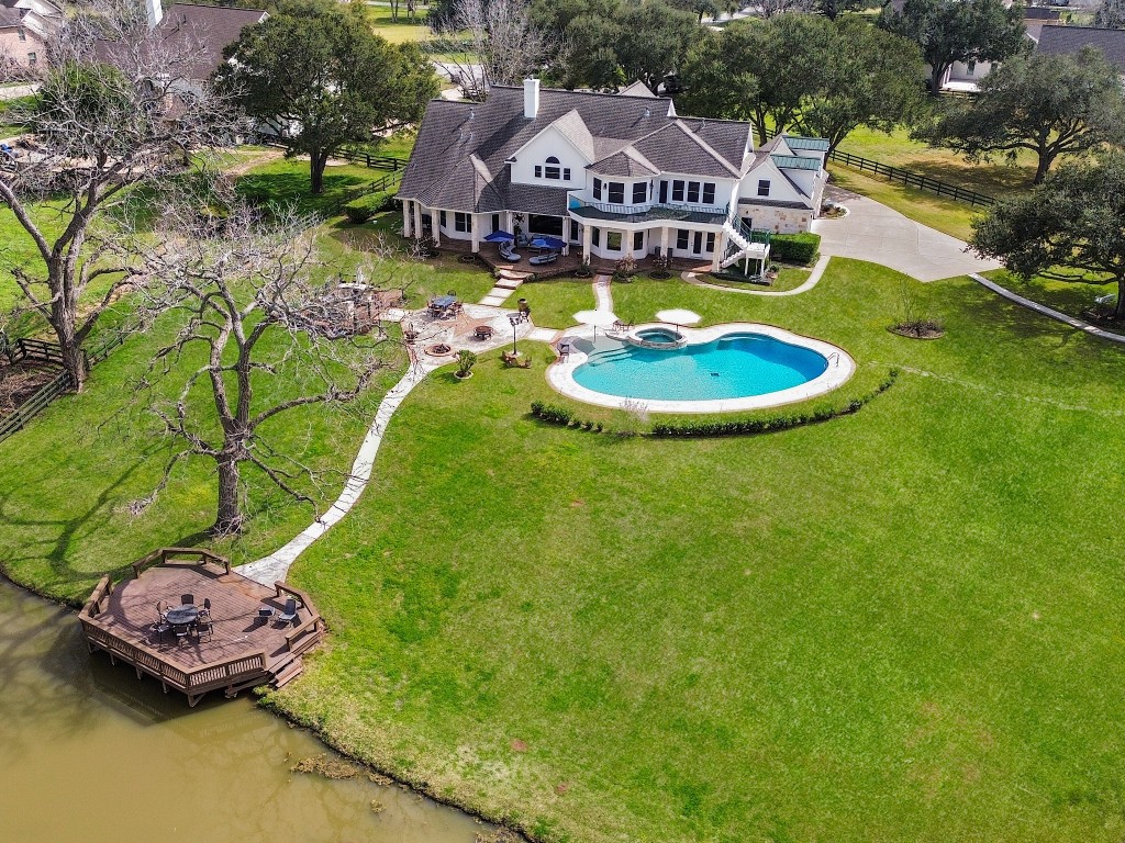 32134 Fulbrook Commons Fulshear, TX 77441 - Photo 3 of 49 An impressive aerial perspective showcasing the full scope of the property — expansive green space, custom pool, private pier access, and sweeping waterfront views that highlight the estate’s exceptional scale and setting.