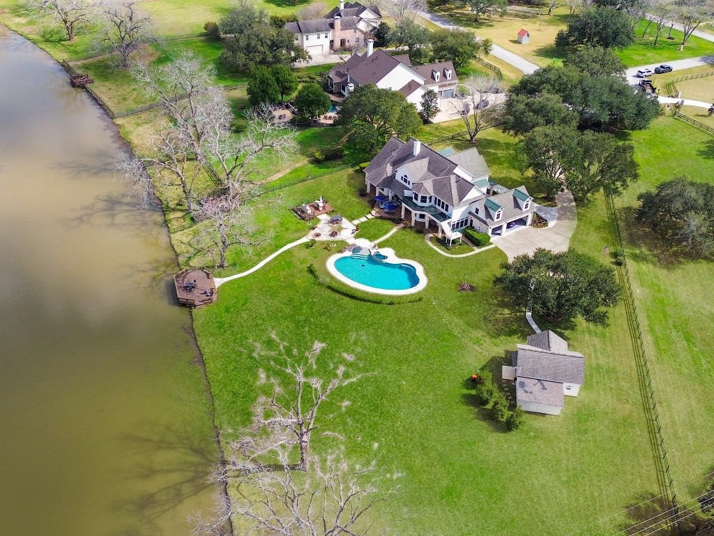 32134 Fulbrook Commons Fulshear, TX 77441 - Photo 36 of 49 An elevated aerial view highlights the full grandeur of the estate — expansive lawn, custom pool, mature trees, and direct lake frontage in a truly private setting.
