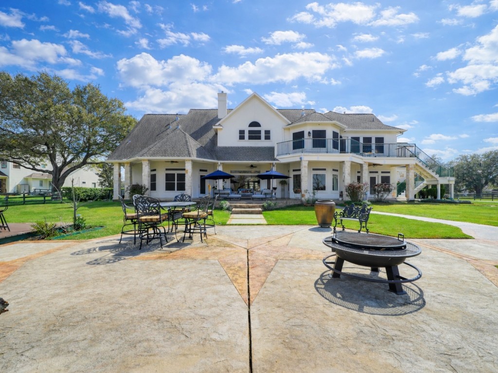 32134 Fulbrook Commons Fulshear, TX 77441 - Photo 39 of 49 A sweeping view of the back elevation showcases the home’s architectural scale, expansive patio spaces, and seamless connection to the surrounding landscape.