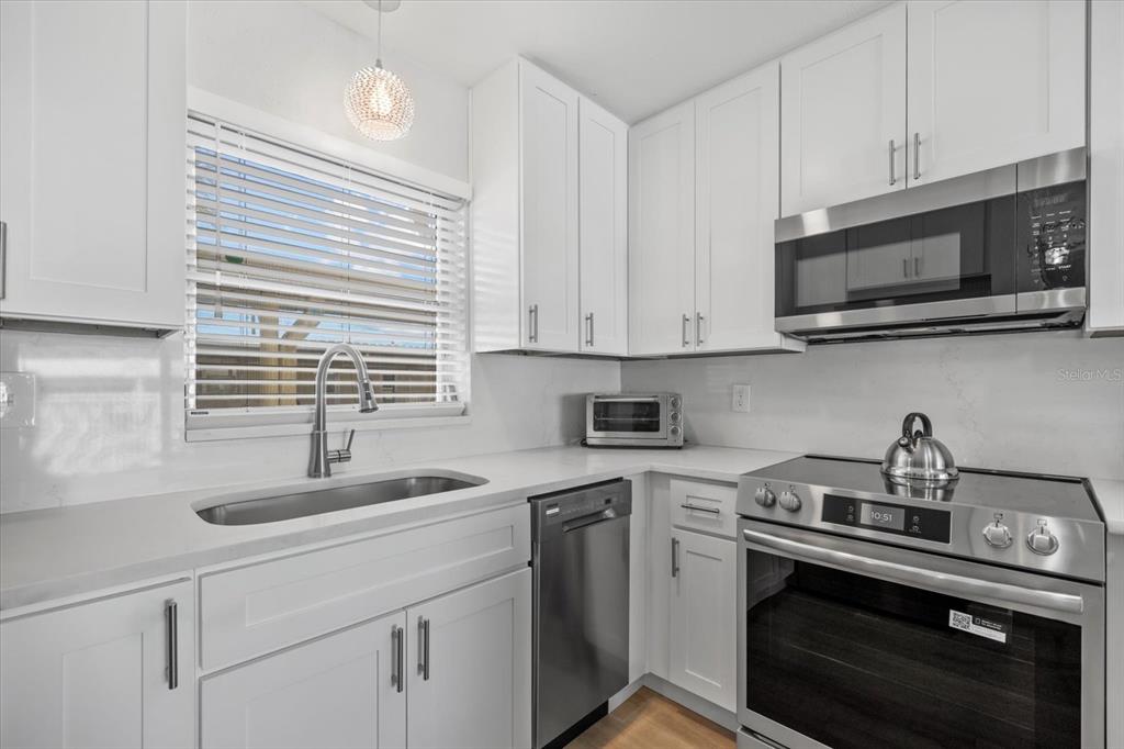5830 Midnight Pass Road, Unit 52 Sarasota, FL 34242 - Photo 9 of 32 a kitchen with stainless steel appliances granite countertop white cabinets a sink and a stove