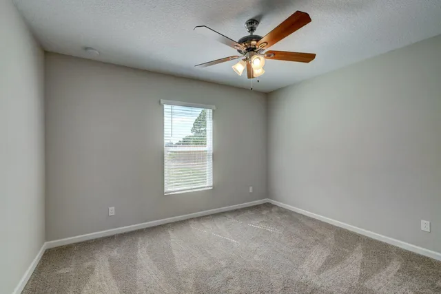 an empty room with closet and a ceiling fan