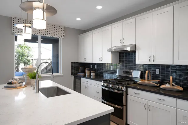 a kitchen with kitchen island granite countertop a sink a center island stainless steel appliances and cabinets