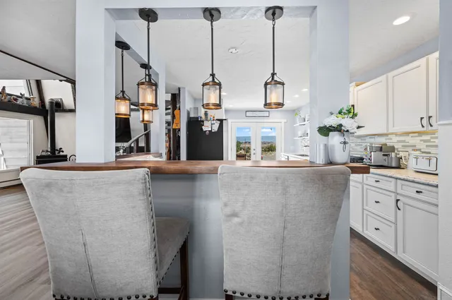 a kitchen with stainless steel appliances kitchen island granite countertop a refrigerator a stove and white cabinets with wooden floor