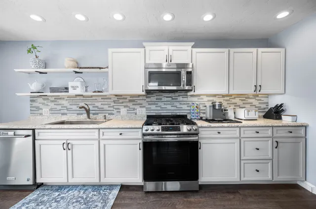 a kitchen with stainless steel appliances granite countertop a stove a sink and a microwave