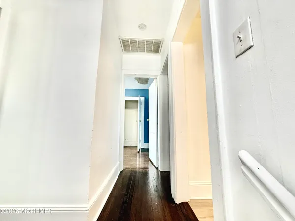 a view of a hallway with wooden floor and a bathroom