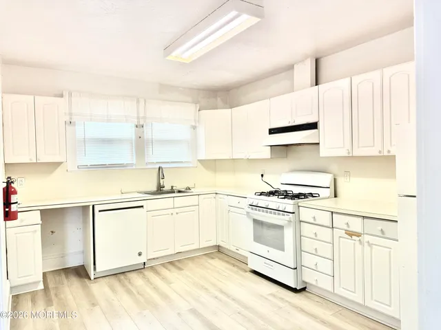 a kitchen with stainless steel appliances granite countertop a stove a sink and white cabinets