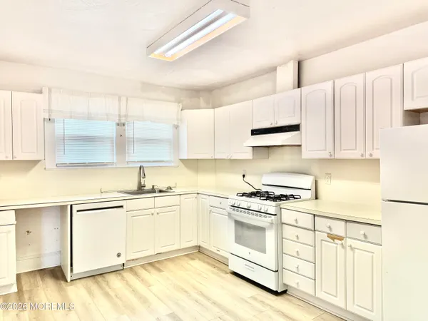 a kitchen with stainless steel appliances granite countertop a stove a sink and white cabinets