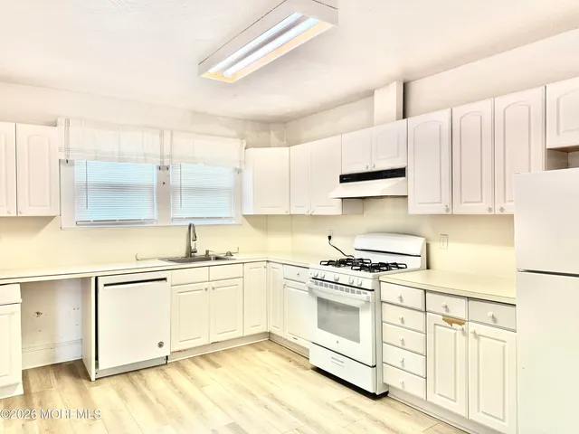 a kitchen with stainless steel appliances granite countertop a stove a sink and white cabinets