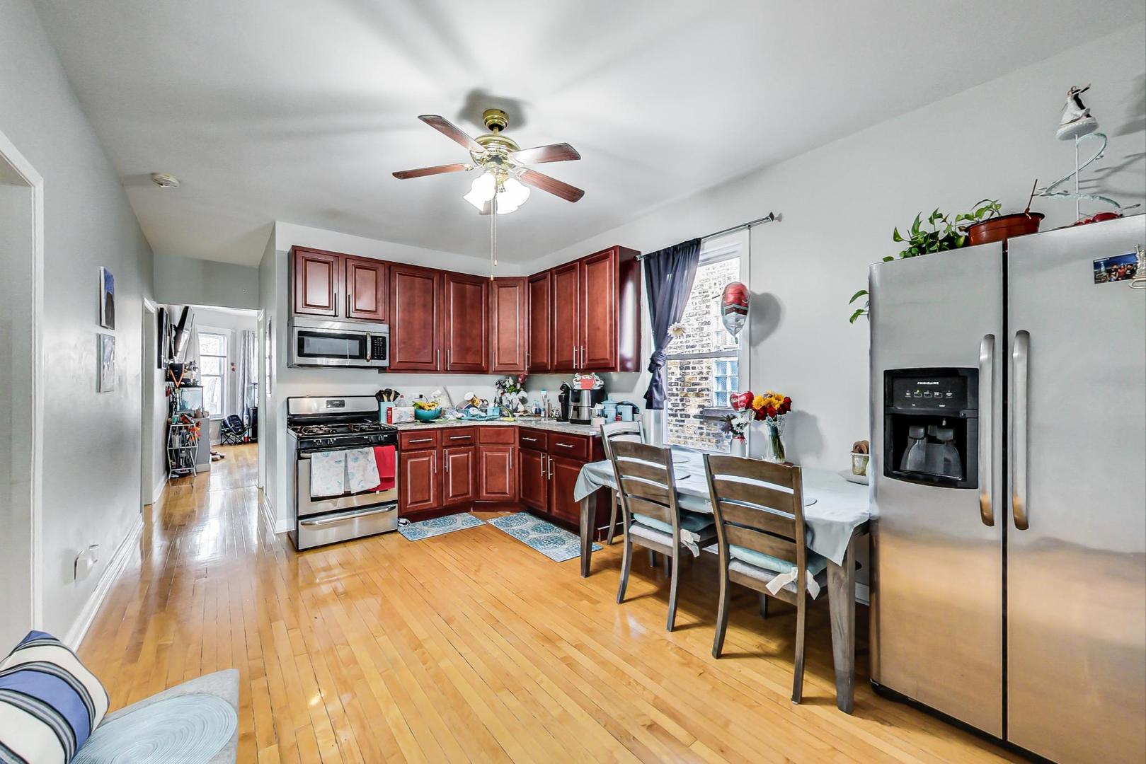 4237 West School Street Chicago, IL 60641 - Photo 27 of 72 a kitchen with stainless steel appliances kitchen island granite countertop a refrigerator a stove a sink a dining table and chairs with wooden floor