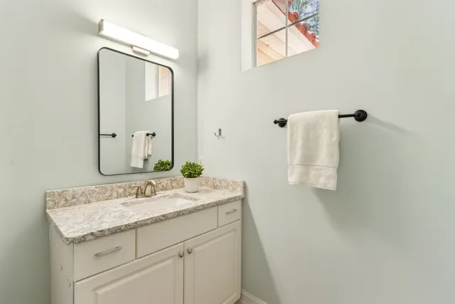 a bathroom with a granite countertop sink and a mirror