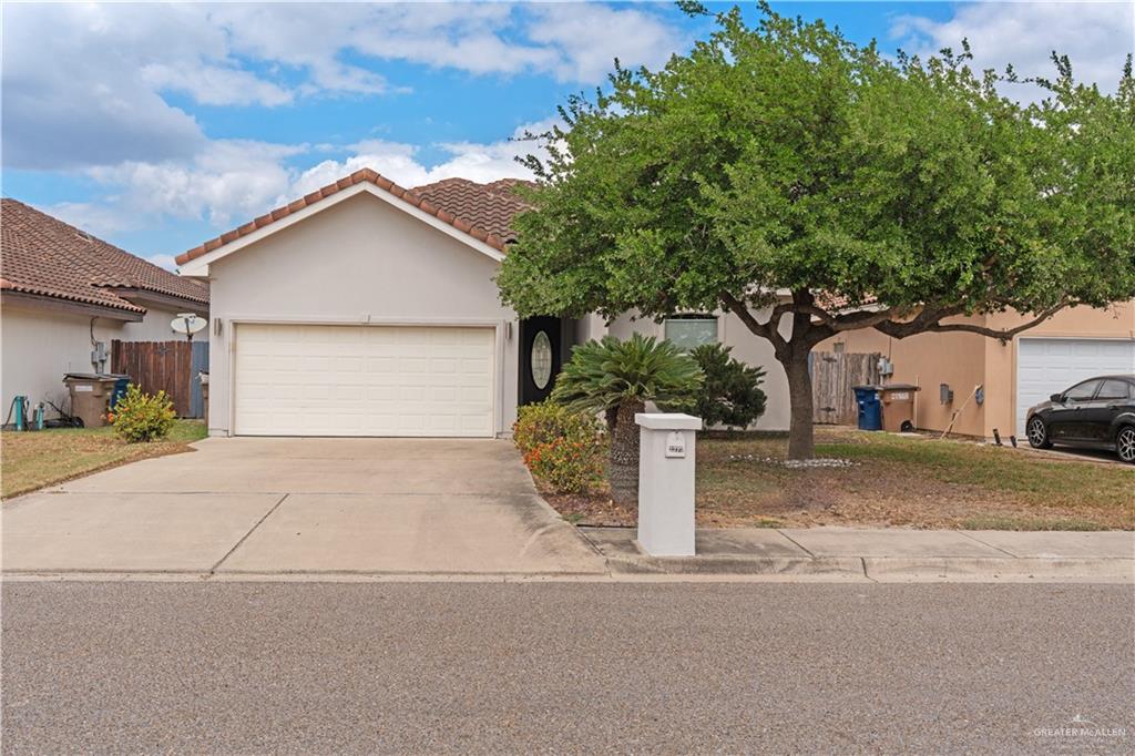 View of front facade with a garage, concrete driveway, stucco siding, and a tile roof