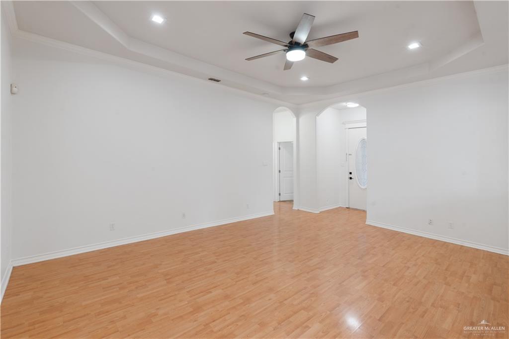 3315 Omega Street Edinburg, TX 78539 - Photo 3 of 19 Empty room with a tray ceiling, arched walkways, a ceiling fan, light wood-style flooring, and recessed lighting