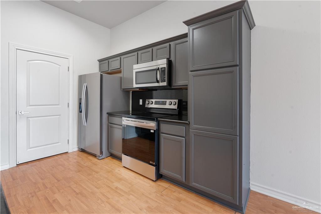 3315 Omega Street Edinburg, TX 78539 - Photo 4 of 19 Kitchen with stainless steel appliances, dark countertops, gray cabinetry, and light wood finished floors