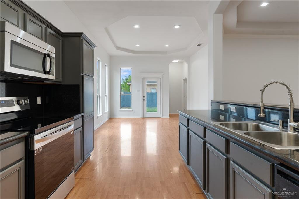 3315 Omega Street Edinburg, TX 78539 - Photo 8 of 19 Kitchen with dark countertops, a raised ceiling, stainless steel appliances, light wood finished floors, and gray cabinets