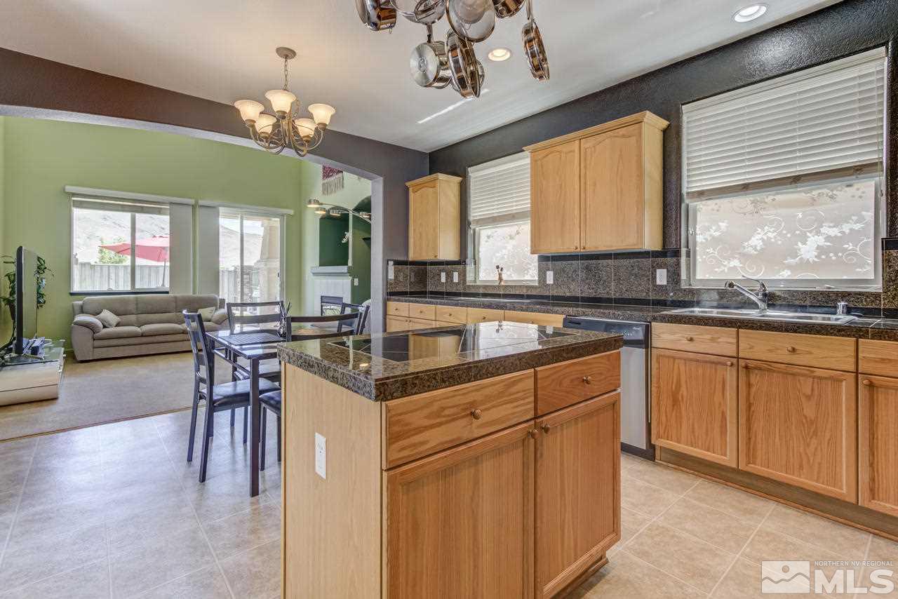 9070 Jack Hammer Drive Reno, NV 89521 - Photo 11 of 40 a open kitchen with stainless steel appliances granite countertop a stove top oven a sink dishwasher a dining table and chairs with wooden floor