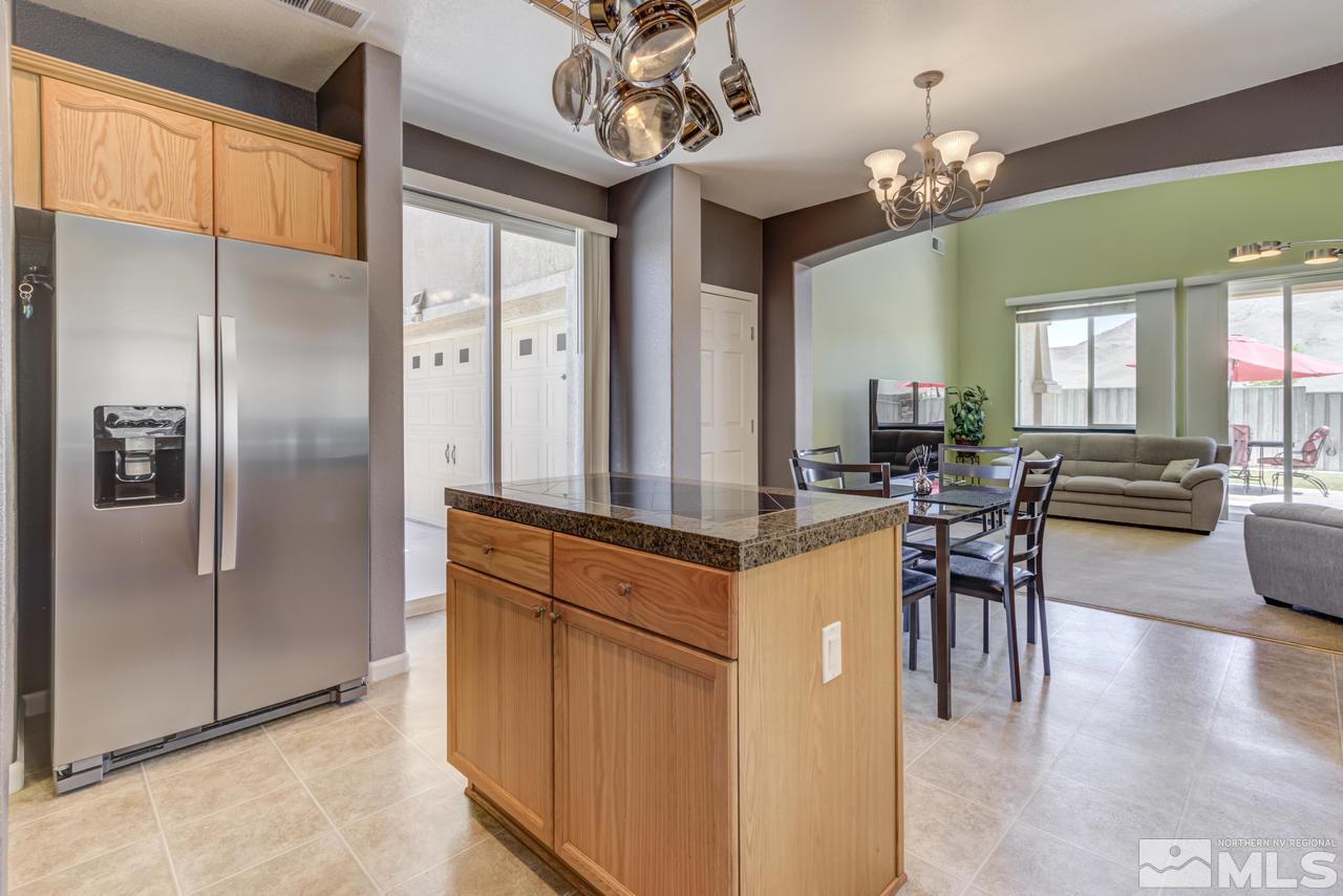 9070 Jack Hammer Drive Reno, NV 89521 - Photo 12 of 40 a kitchen with stainless steel appliances kitchen island granite countertop a refrigerator a stove a dining table and chairs with wooden floor