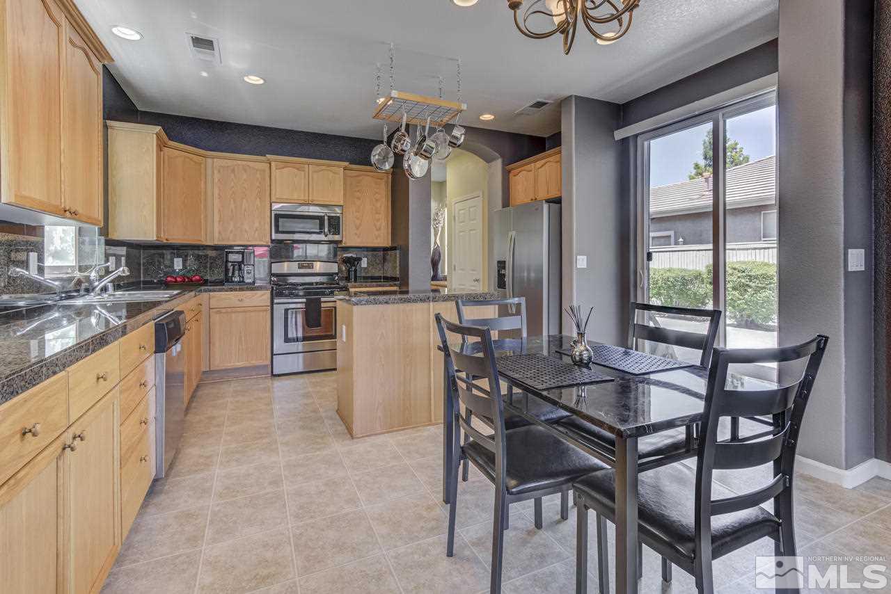 9070 Jack Hammer Drive Reno, NV 89521 - Photo 13 of 40 a kitchen with stainless steel appliances kitchen island granite countertop a table chairs sink and cabinets