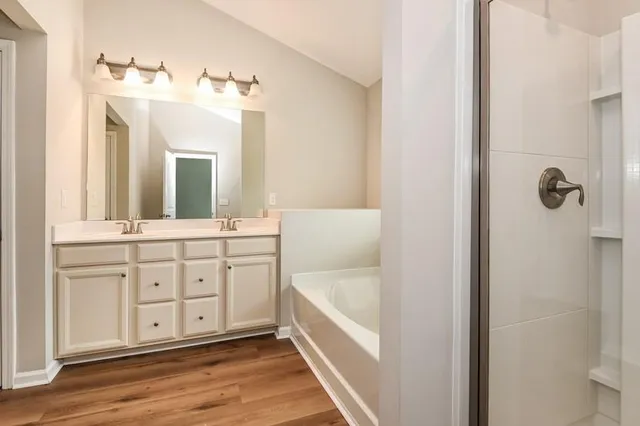 a bathroom with a double vanity sink a mirror a bathtub and