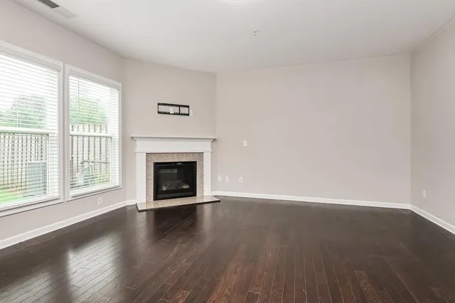 an empty room with wooden floor fireplace and windows