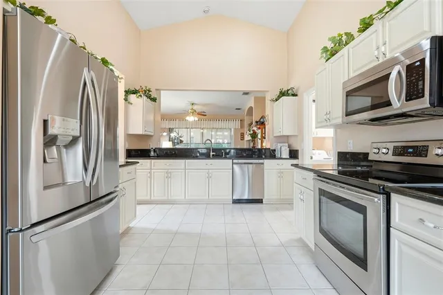 a kitchen with stainless steel appliances granite countertop a refrigerator a stove and a sink
