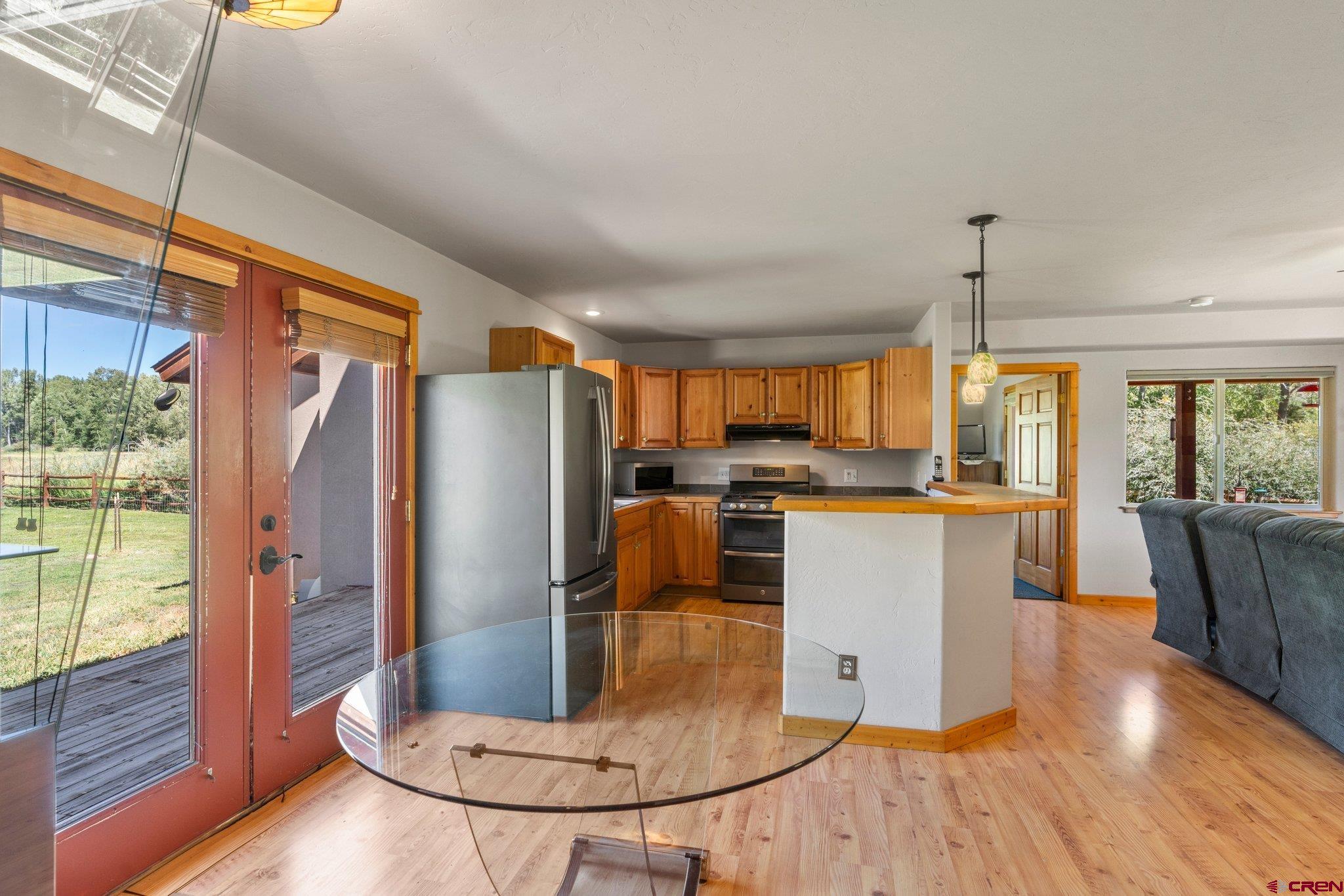 115 Pine River Ranch Circle Bayfield, CO 81122 - Photo 10 of 30 a kitchen with stainless steel appliances granite countertop a refrigerator a stove top oven and a dining table with wooden floor