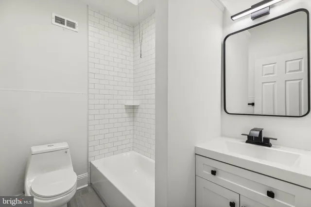 a bathroom with a toilet a sink a mirror and vanity