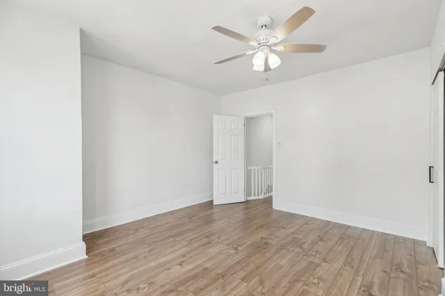 an empty room with wooden floor and a ceiling fan