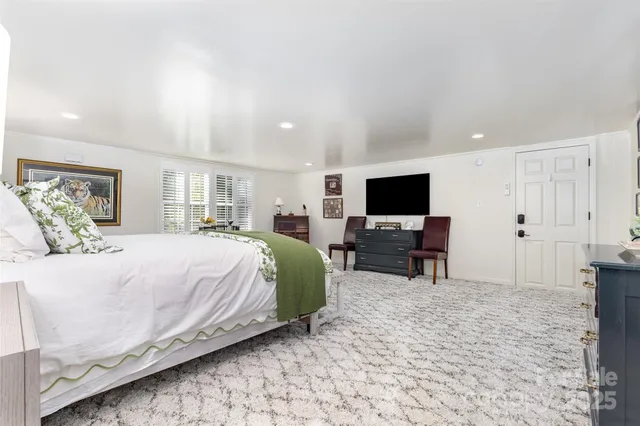 a spacious bedroom with a bed and a flat screen tv