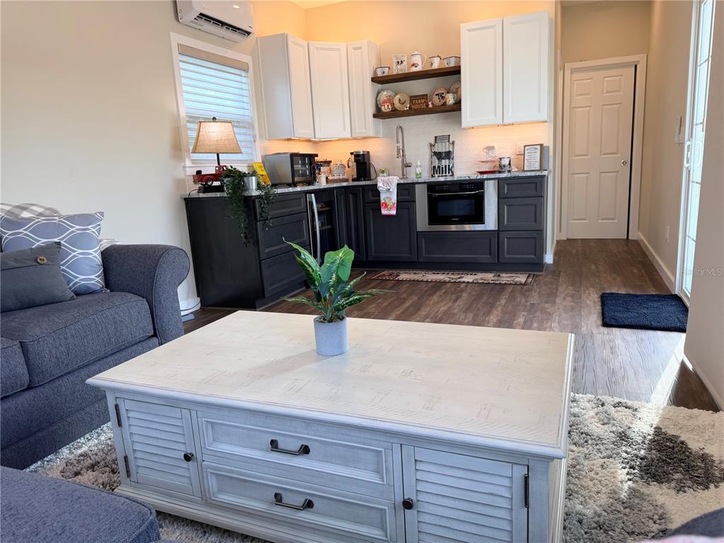 9465 Southeast 47th Way Webster, FL 33597 - Photo 13 of 32 a kitchen with stainless steel appliances kitchen island granite countertop a refrigerator a stove a sink dishwasher and a dining table with wooden floor