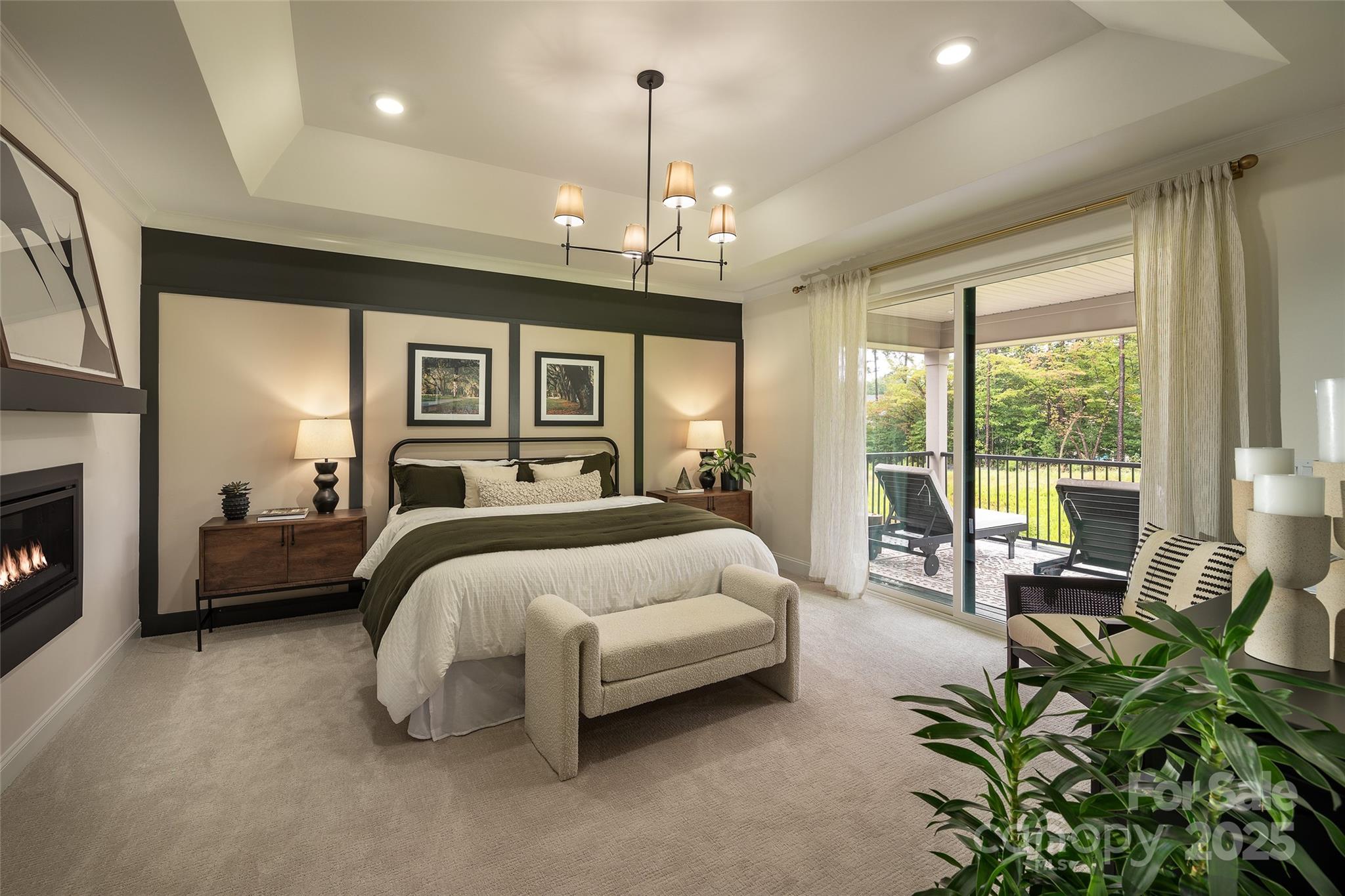 604 Hyder Trail Tega Cay, SC 29708 - Photo 13 of 44 a spacious bedroom with a bed a chandelier couches and a fireplace with the potted plants