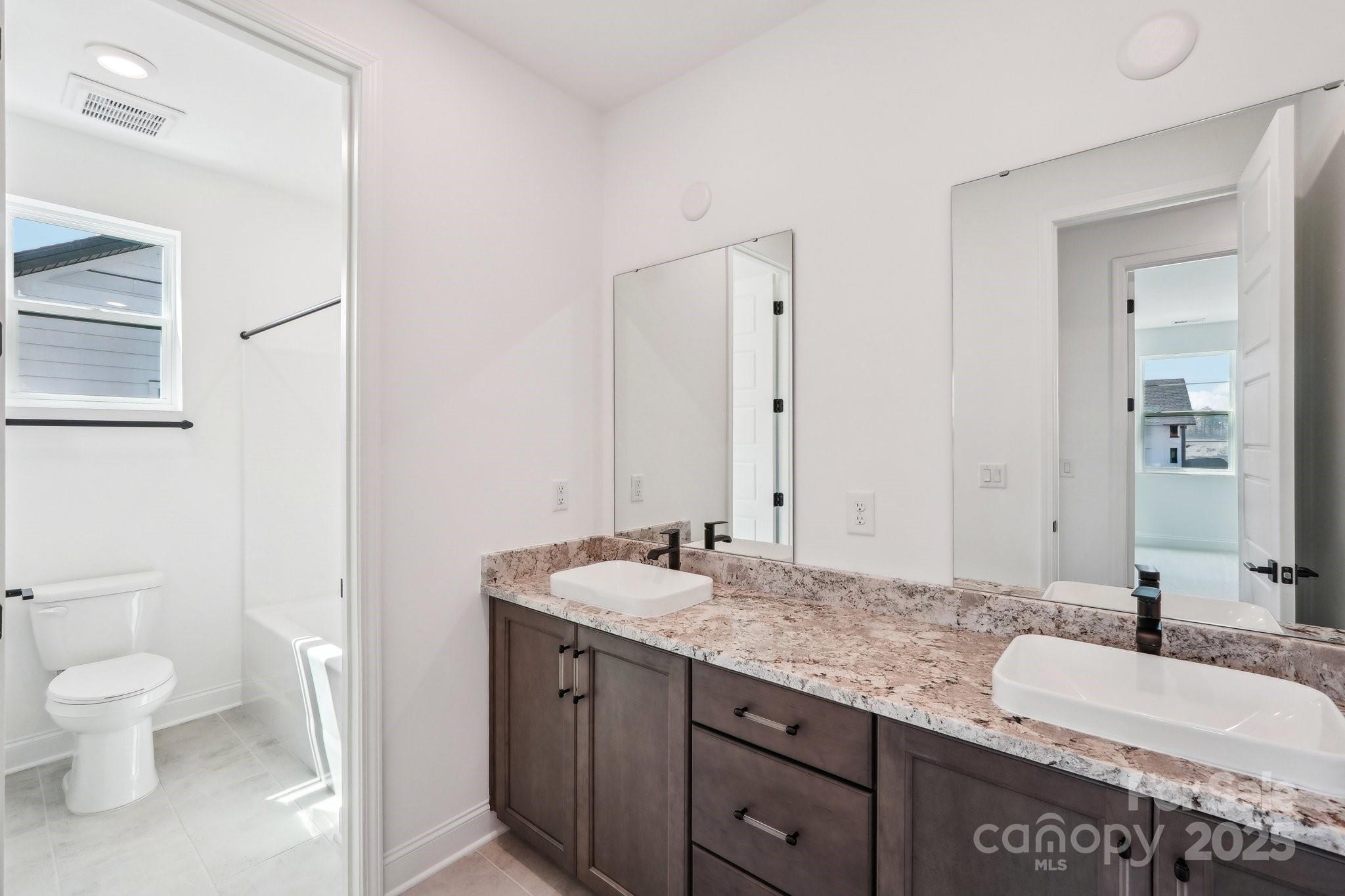 604 Hyder Trail Tega Cay, SC 29708 - Photo 35 of 44 a bathroom with a granite countertop sink a toilet and a mirror