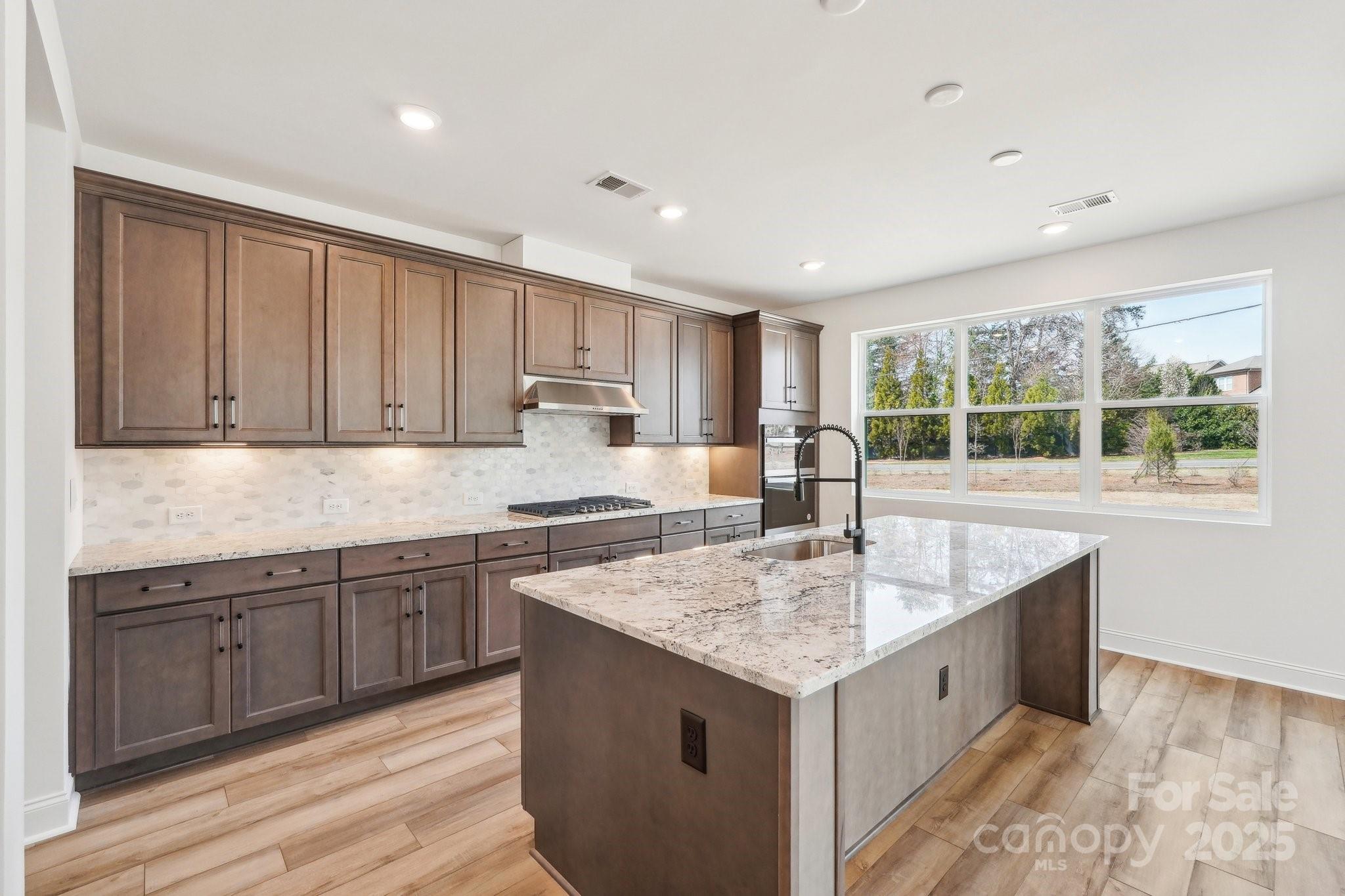 604 Hyder Trail Tega Cay, SC 29708 - Photo 7 of 44 a kitchen with granite countertop sink stove and cabinets