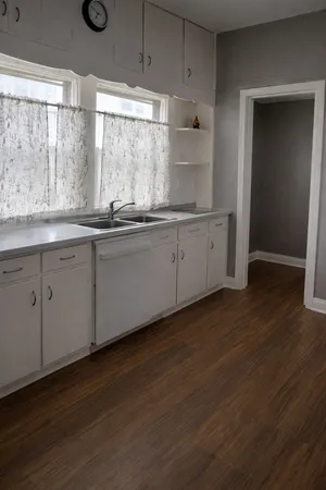 a kitchen with granite countertop white cabinets and a wooden floor