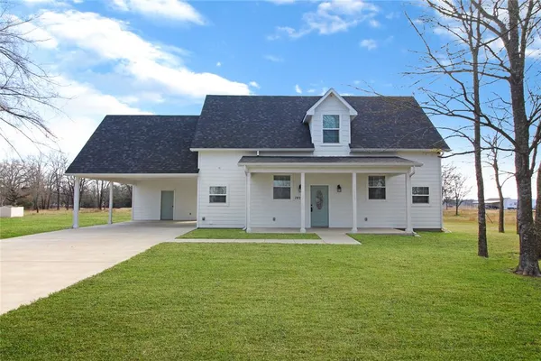 a front view of a house with a yard and trees