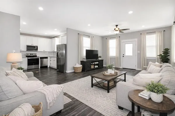 a living room with furniture kitchen view and a window