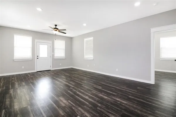 an empty room with wooden floor and windows