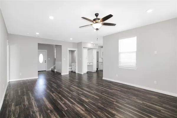 a view of an empty room with wooden floor and window