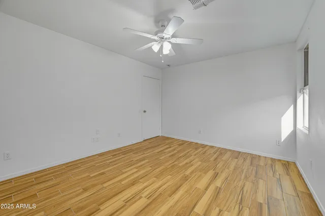 a view of an empty room with wooden floor and a window