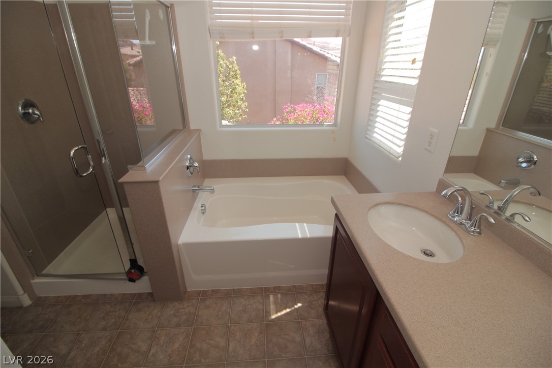 9289 Valley Ranch Avenue Las Vegas, NV 89178 - Photo 18 of 29 A well-appointed bath features a deep soaking tub, glass-enclosed shower, and a vanity with a large mirror.