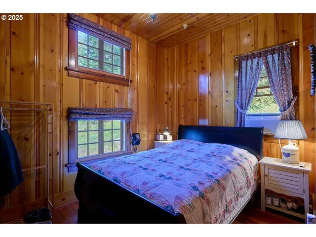 a bedroom with a bed a dresser and windows