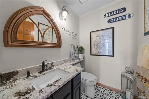 a bathroom with a granite countertop toilet a sink and a mirror