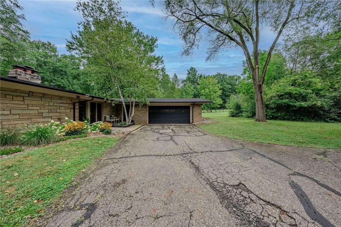 3381 Barrett Road Akron, OH 44333 - Photo 43 of 50 View of front of home featuring a garage, asphalt driveway, a front lawn, stone siding, and a chimney
